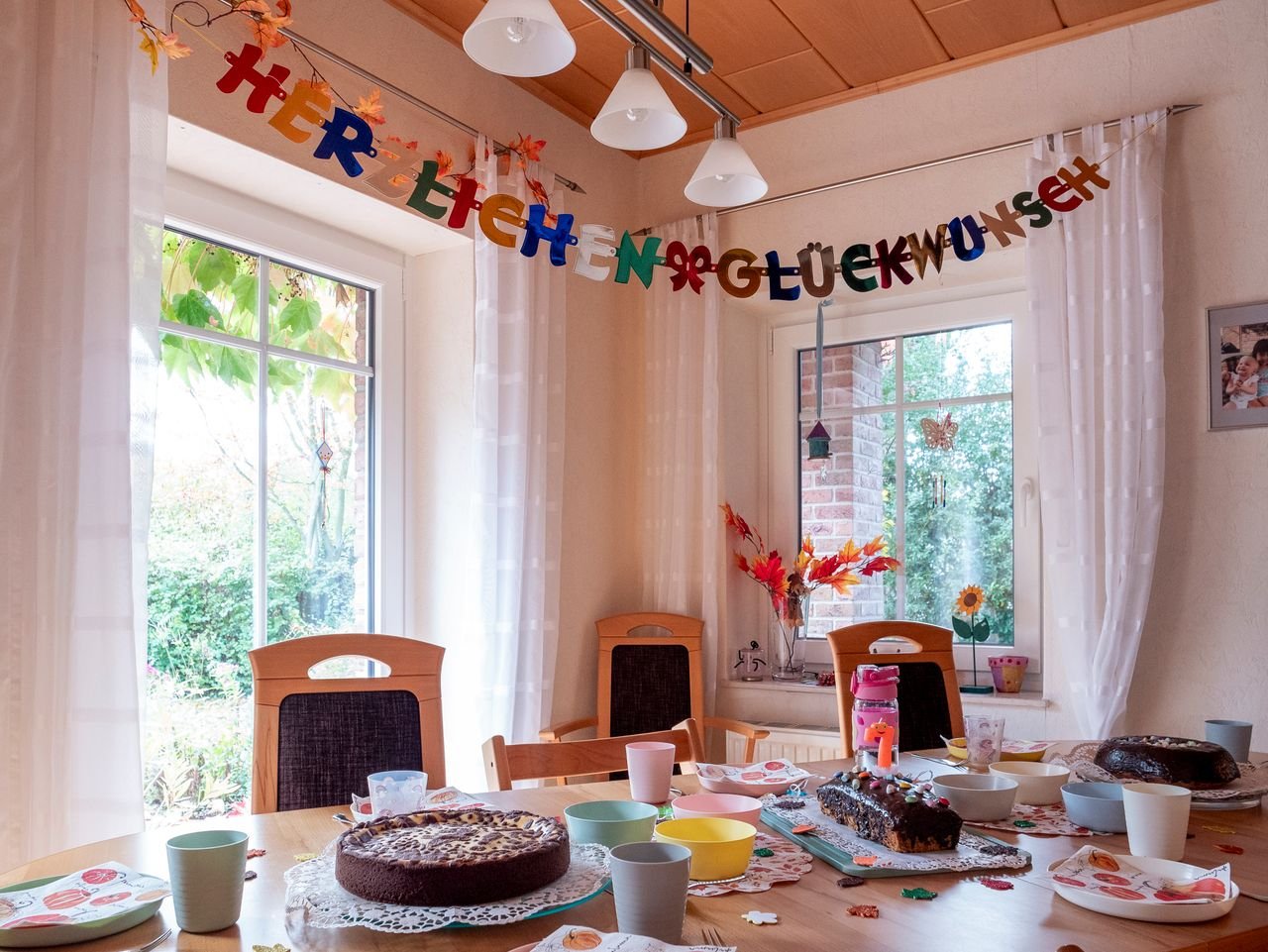 Festive indoor celebration table with cakes and colorful decorations for a joyous occasion.